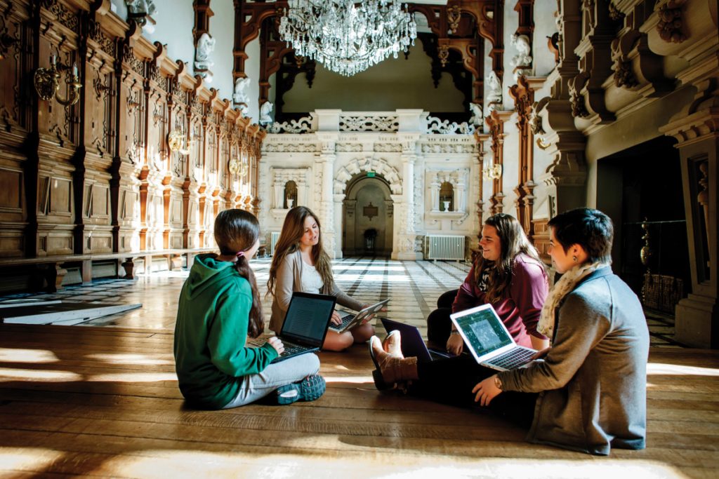 Study abroad students sit on the floor inside Harlaxton Manor, UK