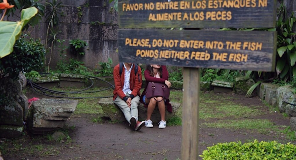 Couple sits behind sign at El Centro de Cartago