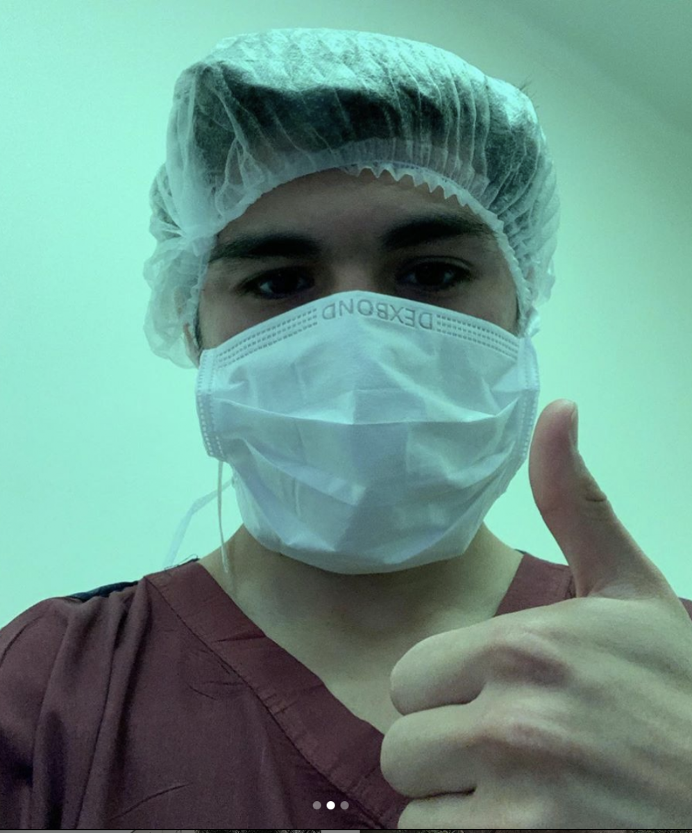 Study abroad student Steven Chavez in hospital gear thumbs up