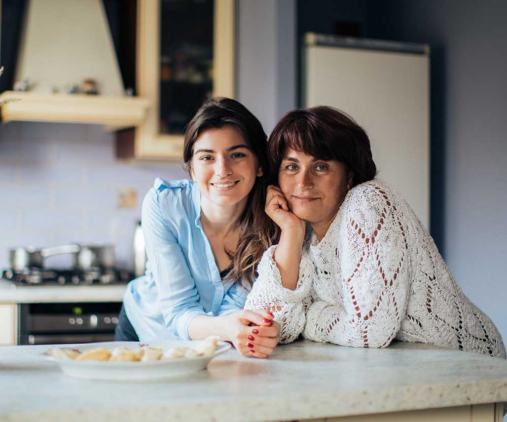 Mother and daughter leaning on kitchen counter