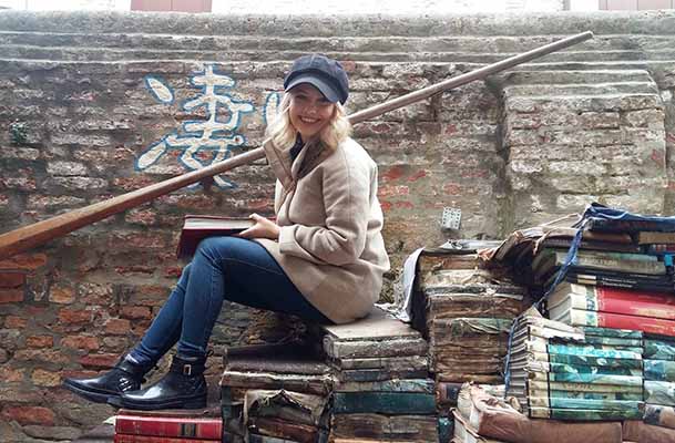 Student posing on books on canal stairs