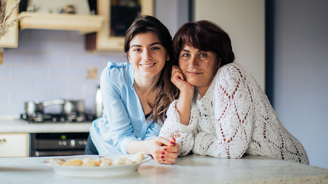 Mother and daughter leaning on kitchen counter