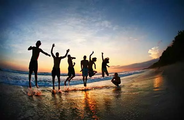 Student group jumping on beach